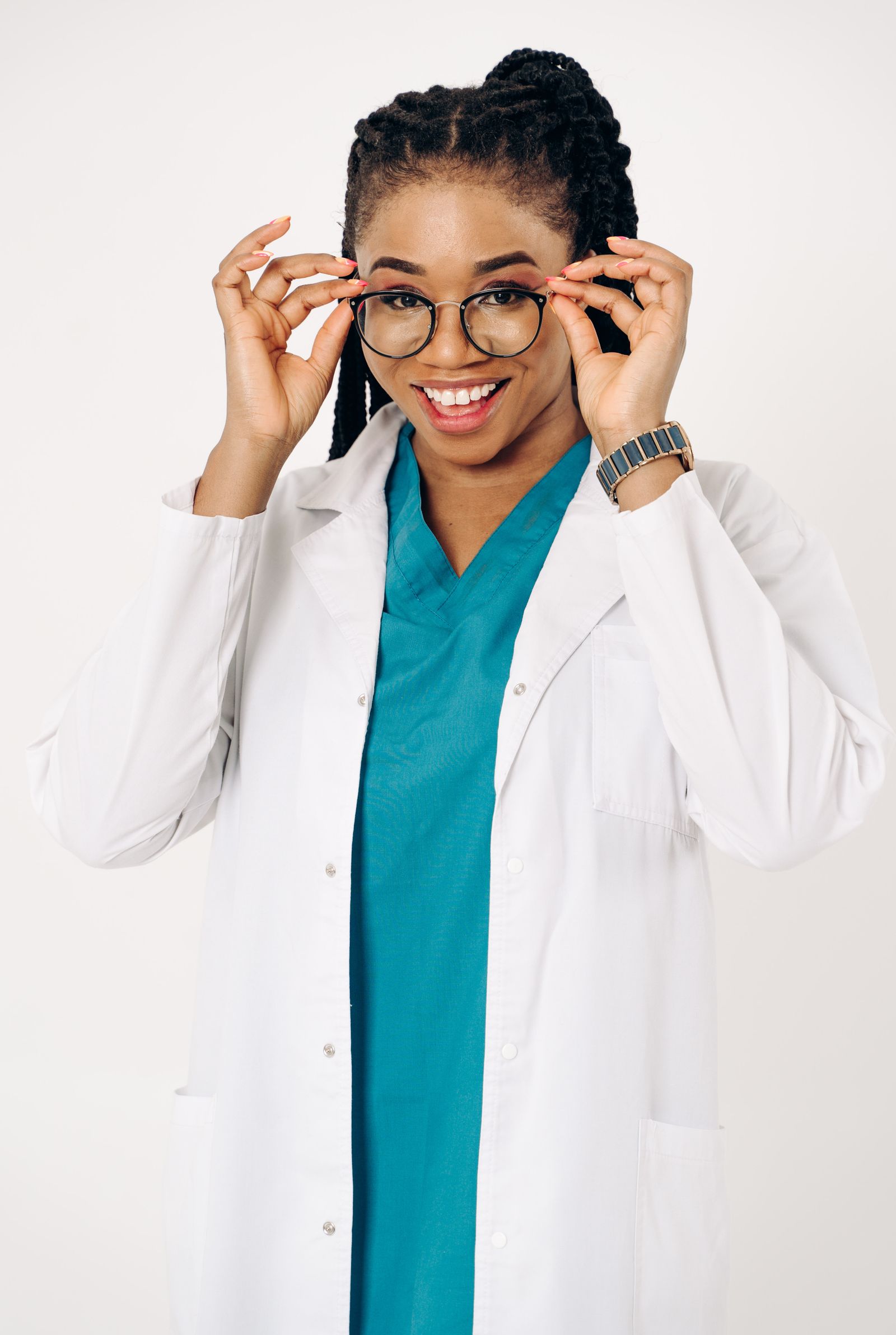 Smiling female doctor in a white coat adjusting her eyeglasses, exuding confidence and professionalism.