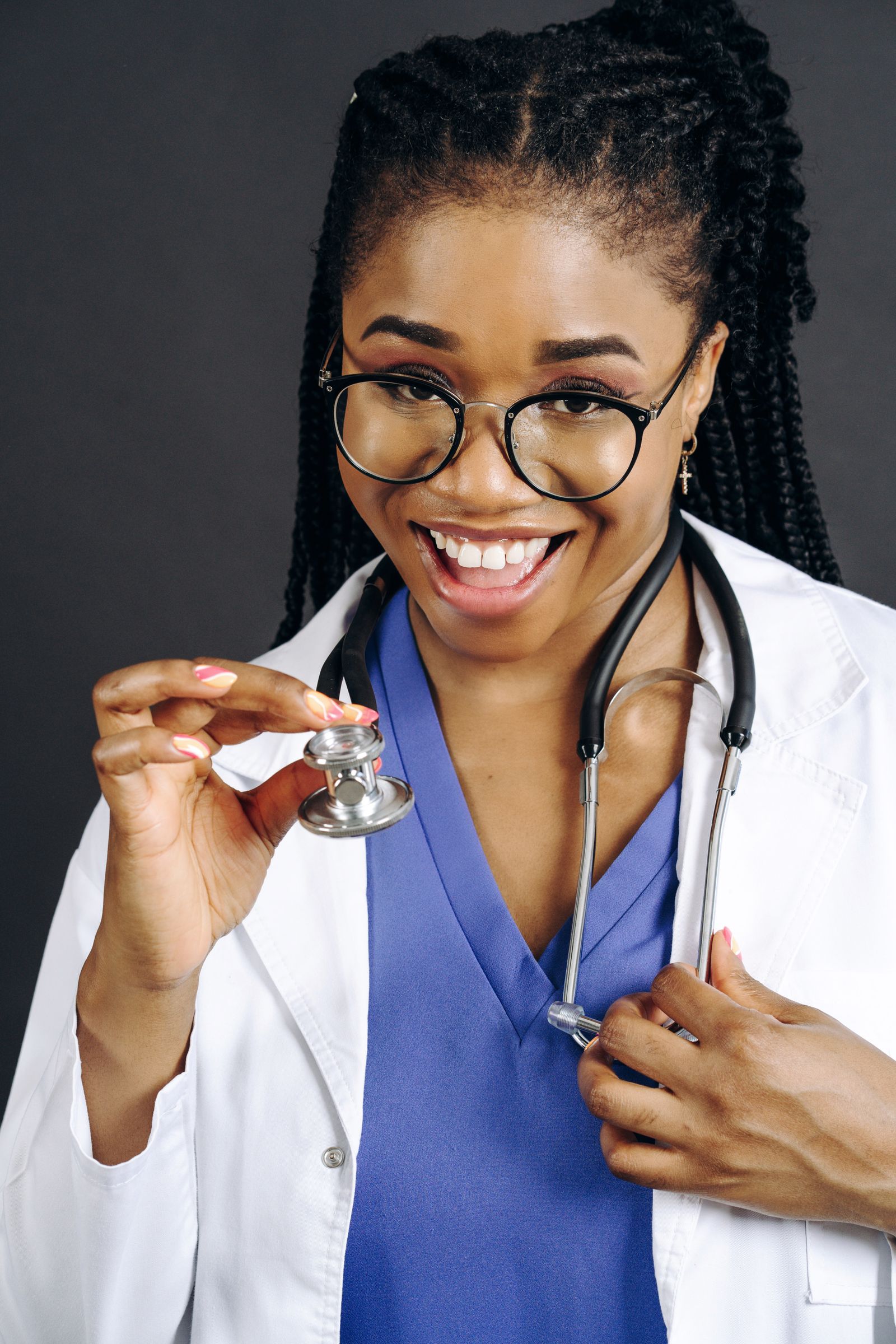 Smiling female doctor in white coat and glasses, holding a stethoscope confidently.